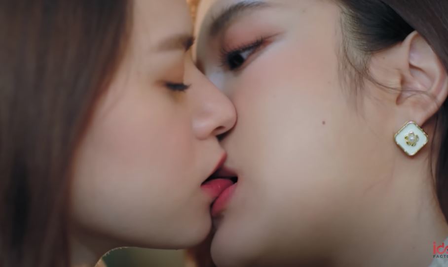 Closeup of Sam biting Mon's lower lip